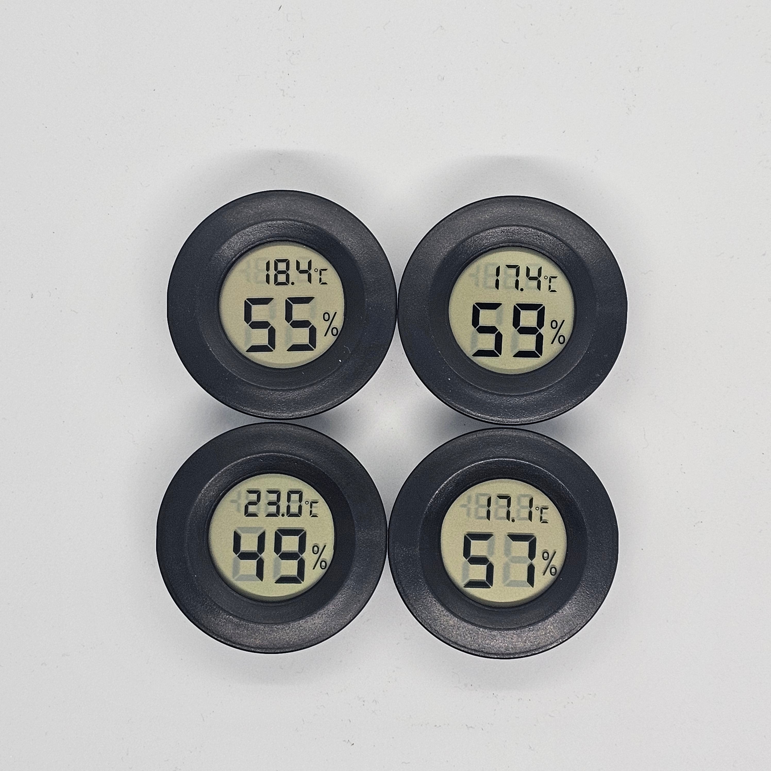 Four digital thermometers and hygrometers with black cases on a white background